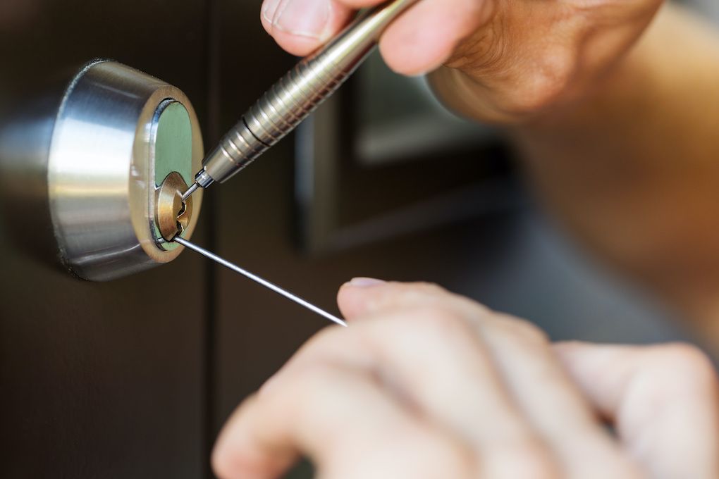Locksmith using a tension tool and pick to open a door lock